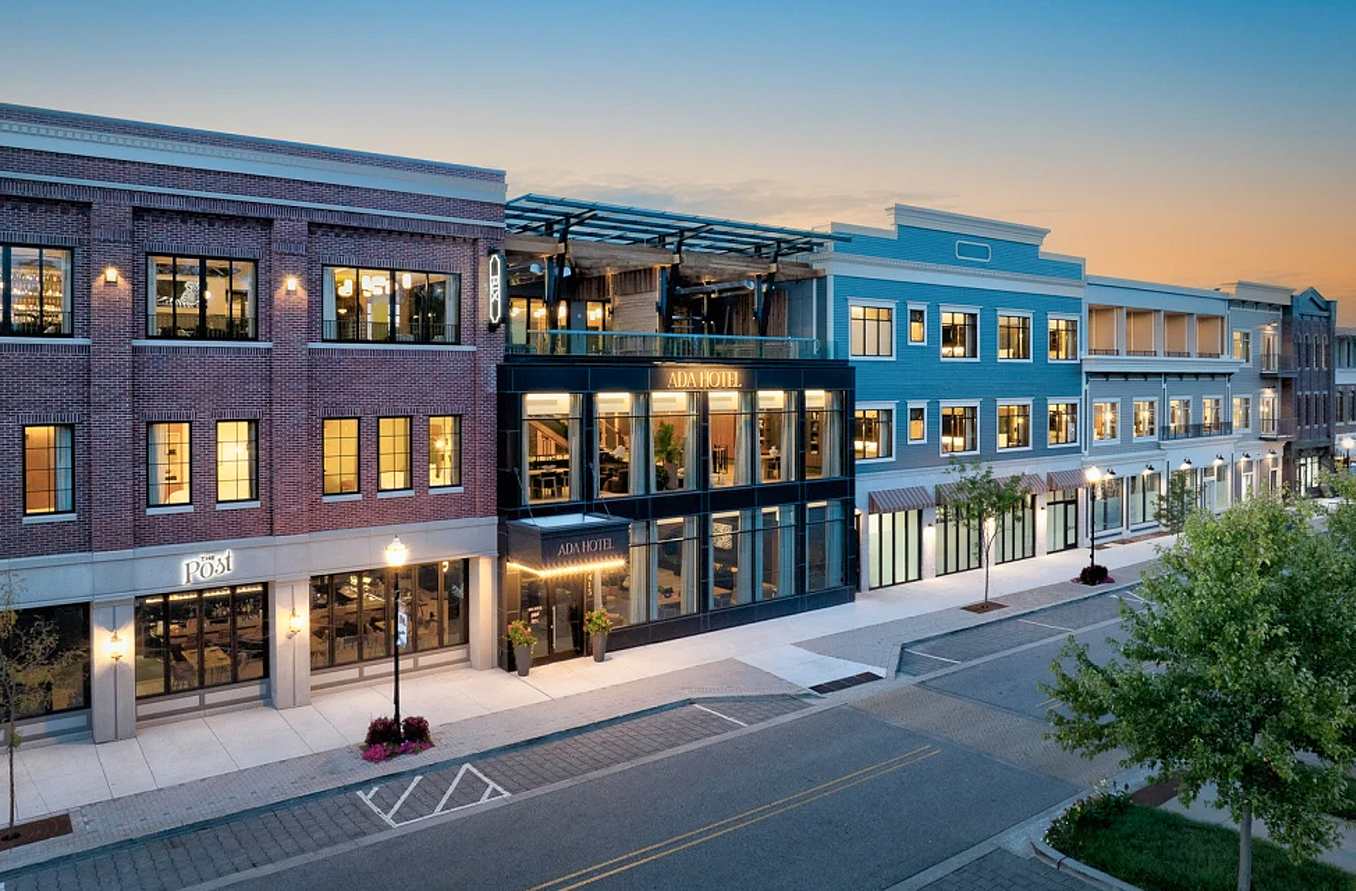 Street view of a  mixed-use building merging historic and contemporary design elements. Building is featuring brick, blue facades, and large glass doors.