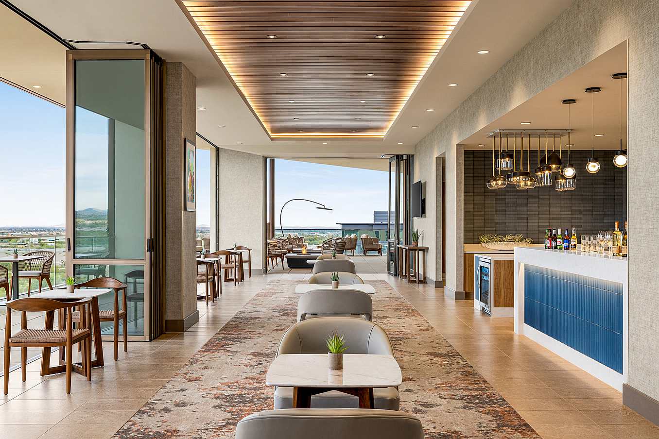 Modern hotel lounge with opening glass doors overlooking outdoor view.