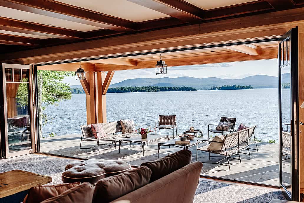 A spacious living room with folding glass walls that offer a stunning view of the serene lake