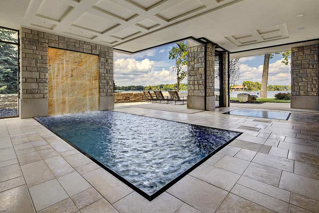 Modern indoor pool with stacking glass doors and stone wall