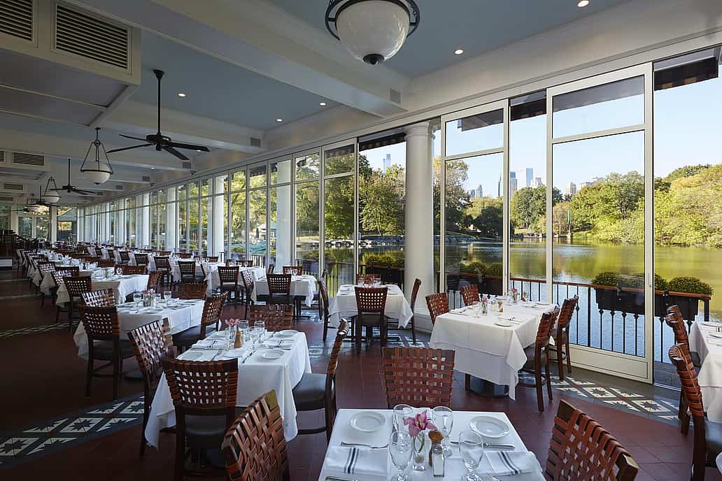 The Loeb Boathouse Central Park, New York, NY | Restaurant with sliding glass doors opening to a scenic lake and trees on a sunny day.