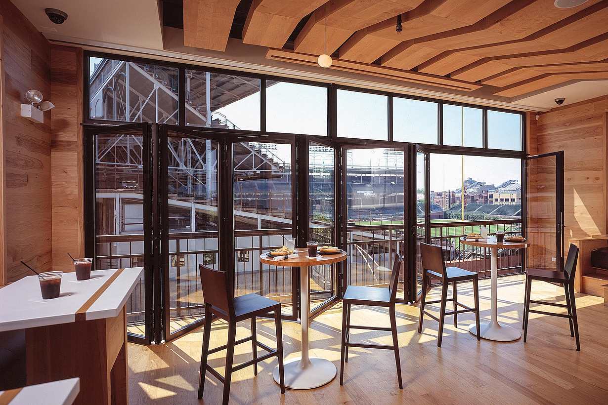 commercial folding glass wall system partially open with view of baseball view for live games