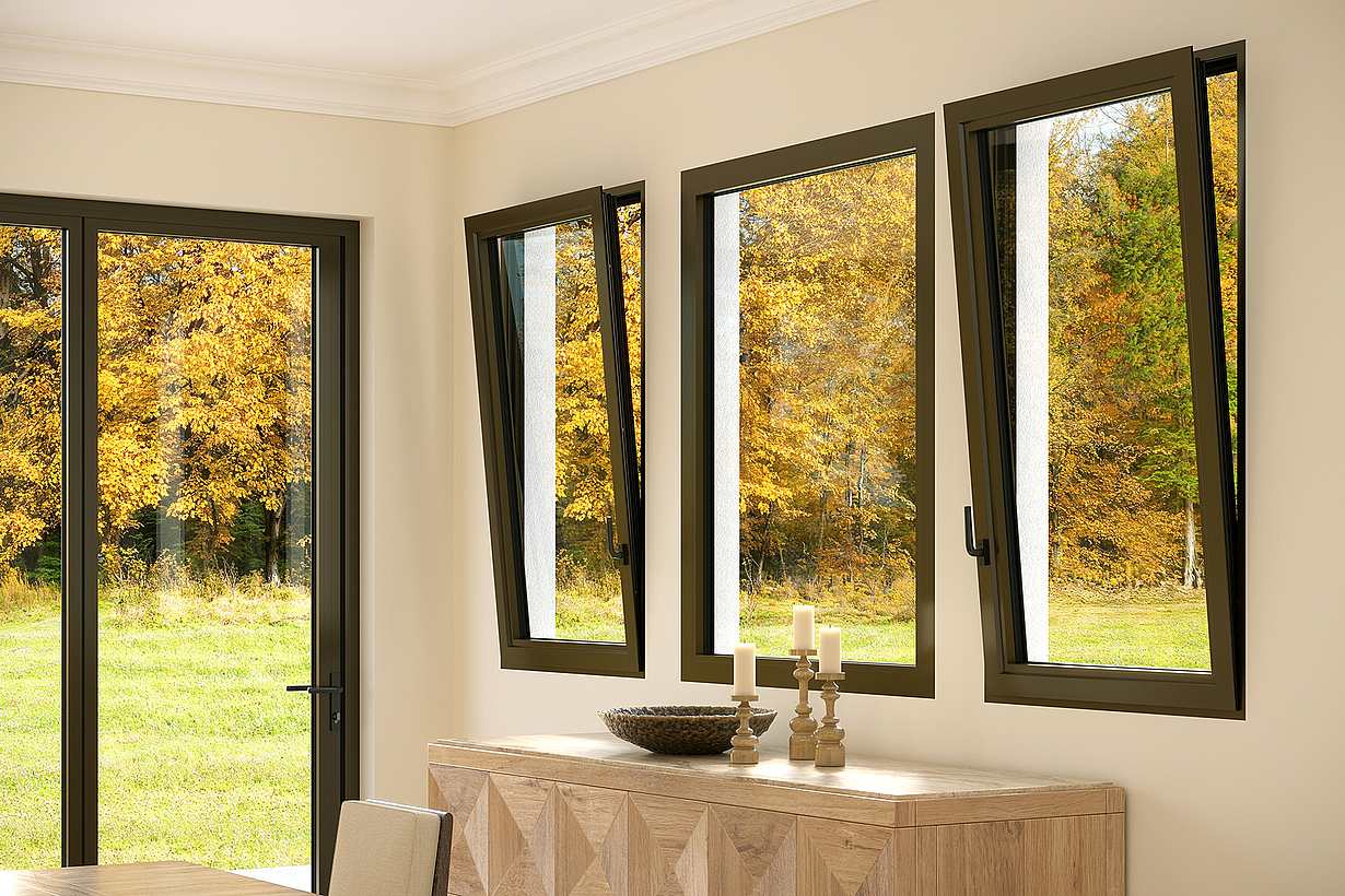 Three open windows, utilizing the tilt function to provide refreshing airflow and ventilation, and a glass door in a room reveal a view of autumn's grassy expanse and golden-leaved trees. 