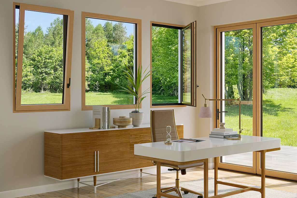 An office with a wooden table features Generation 4 folding glass walls and tilt turn windows, offering a uniform aesthetic and framing views of trees with yellow autumn leaves outside.