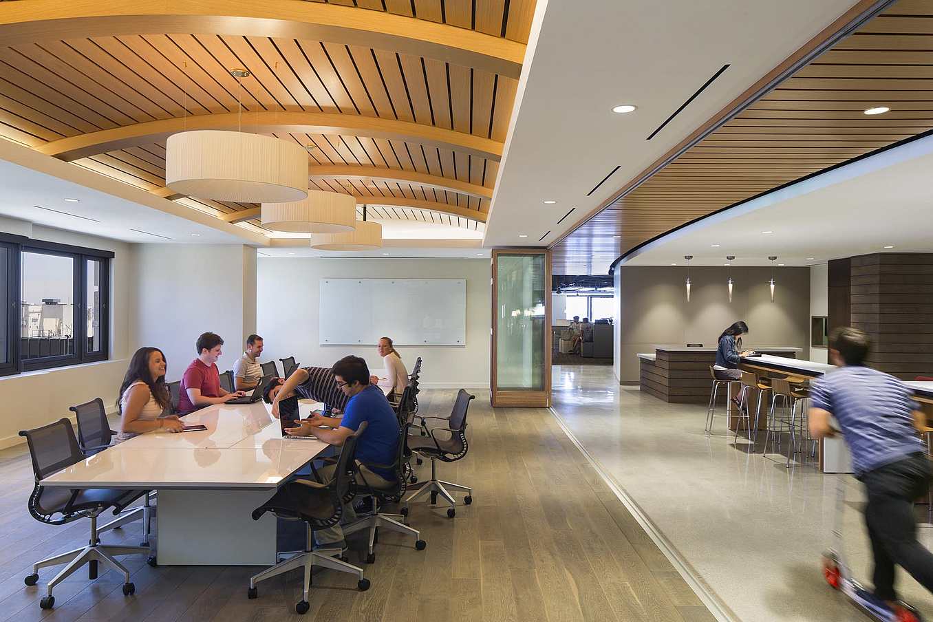 Office space with folding glass walls and a group of people sitting around a table