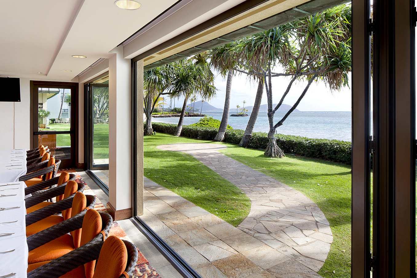 Thermally broken, impact-rated NanaWall SL73 folding glass wall opening interior spaces to the outdoors in a coastal Hawaii installation