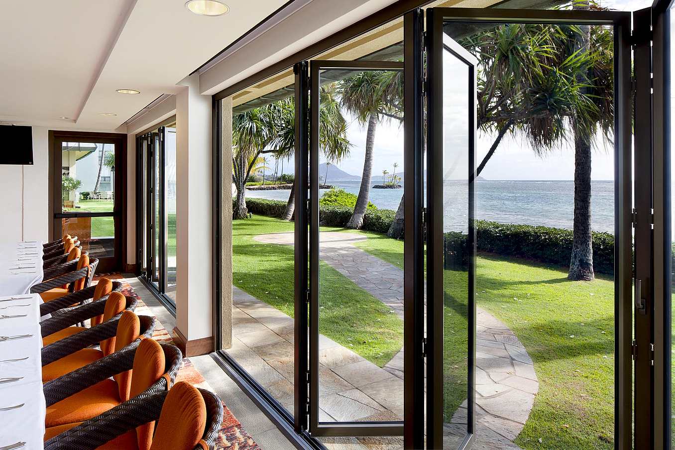 NanaWall SL73 impact-rated folding glass wall system at a coastal club facility in Hawaii, supporting hurricane and wind-load requirements