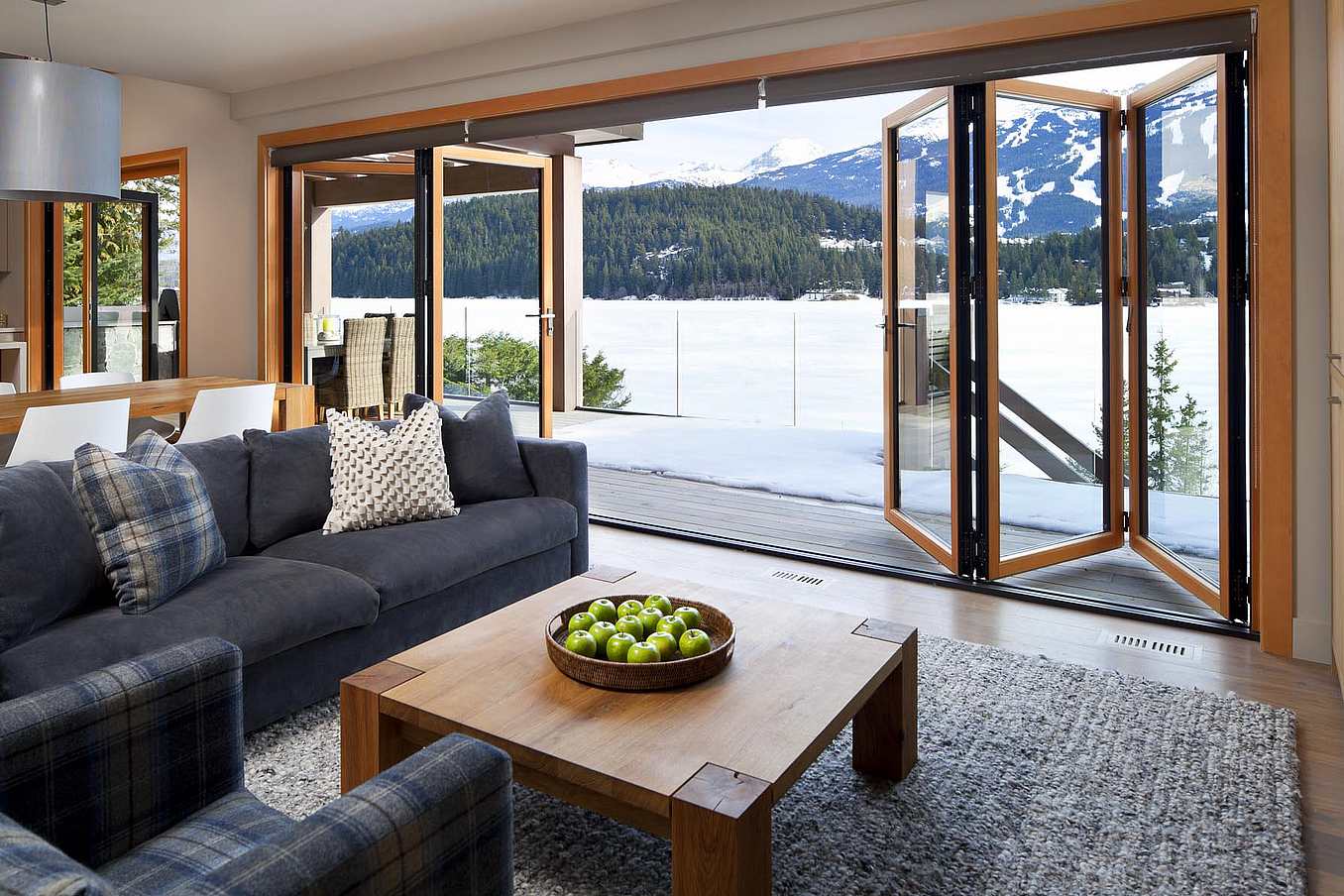 Retractable patio doors in Whistler, BC open to snowy mountain and lake views, offering high‑weather performance