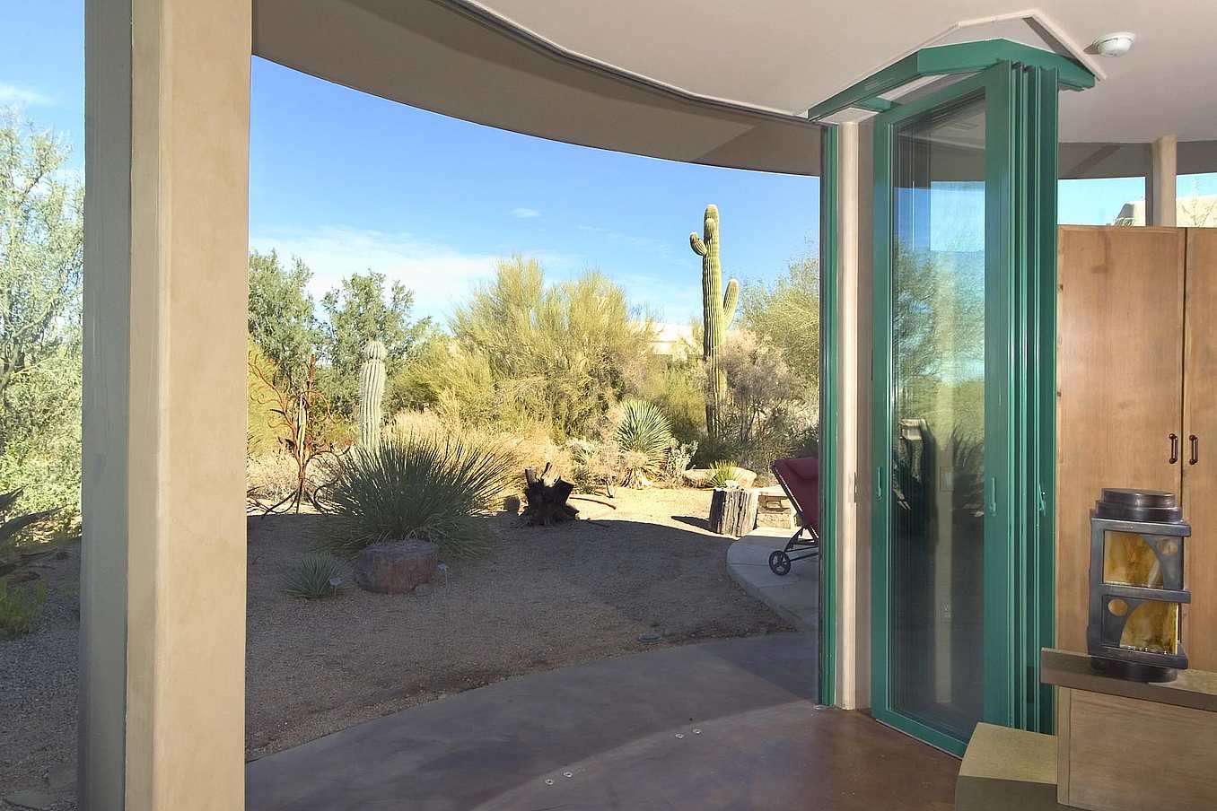 High-performance bifold glass doors open to a desert patio with cactus and clear sky, blending indoor and outdoor spaces
