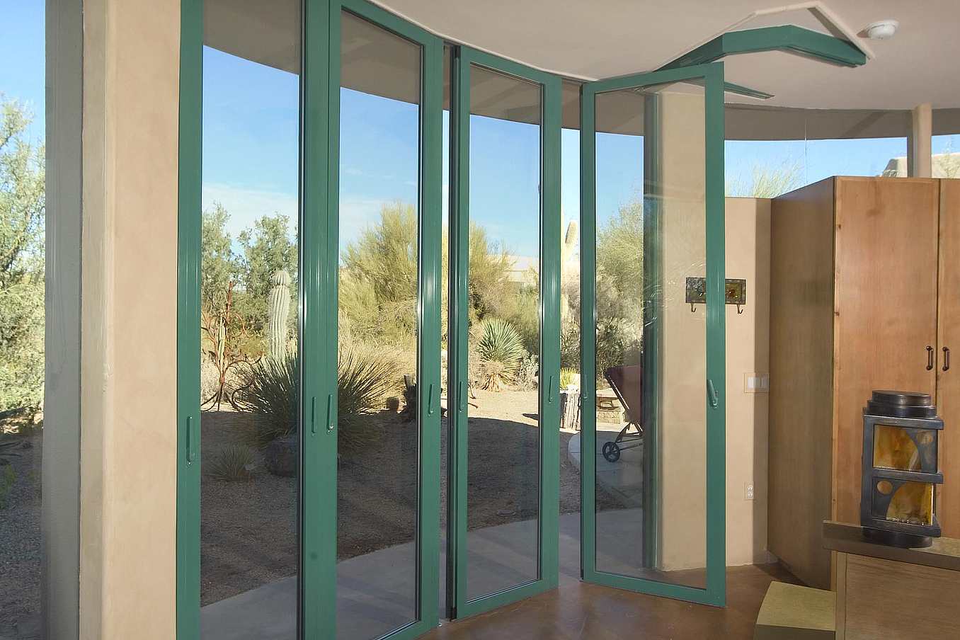 Curved sliding patio doors in Arizona partially open to desert landscape, blending indoor space with outdoor vistas
