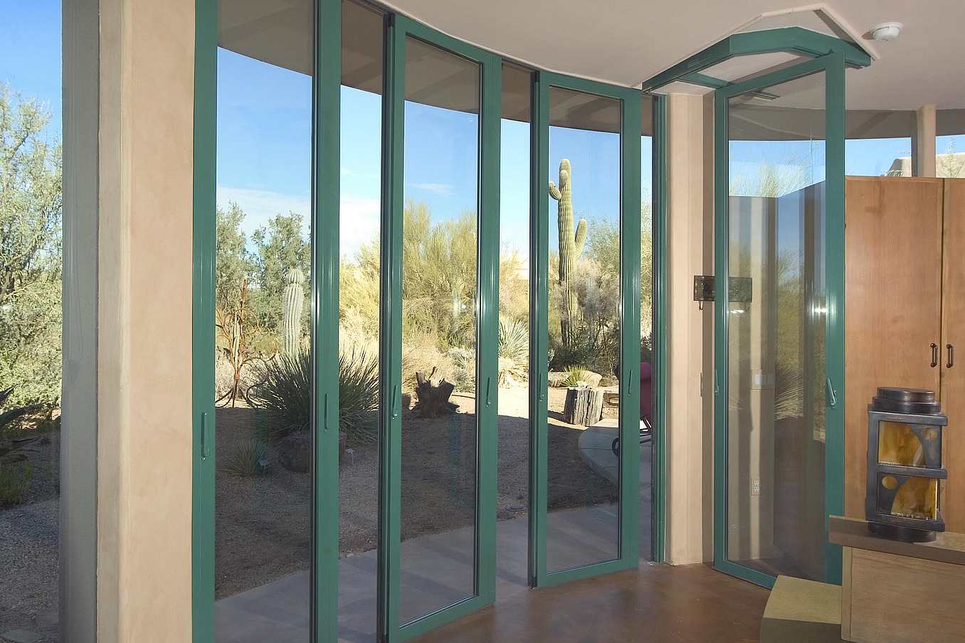 Curved sliding patio doors in Arizona stacking into bay on right, opening to desert views and connecting indoor-outdoor space