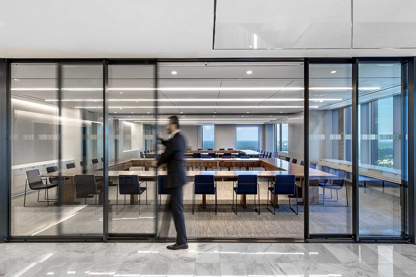 Modern conference room  with sliding glass doors and large windows in a contemporary office building.