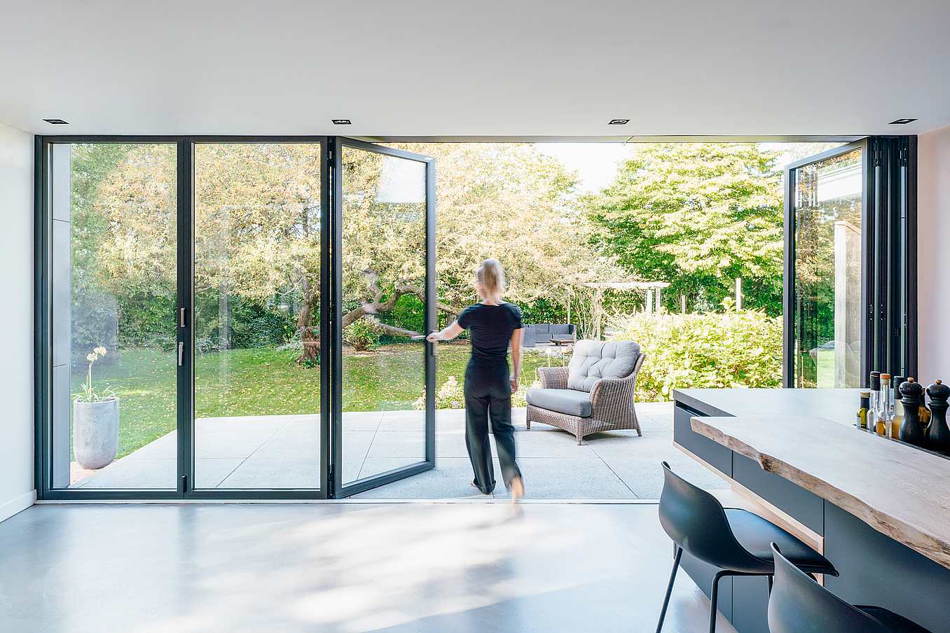 Retractable patio doors enhance a modern residence by seamlessly extending indoor space to the outdoors with clean aesthetics