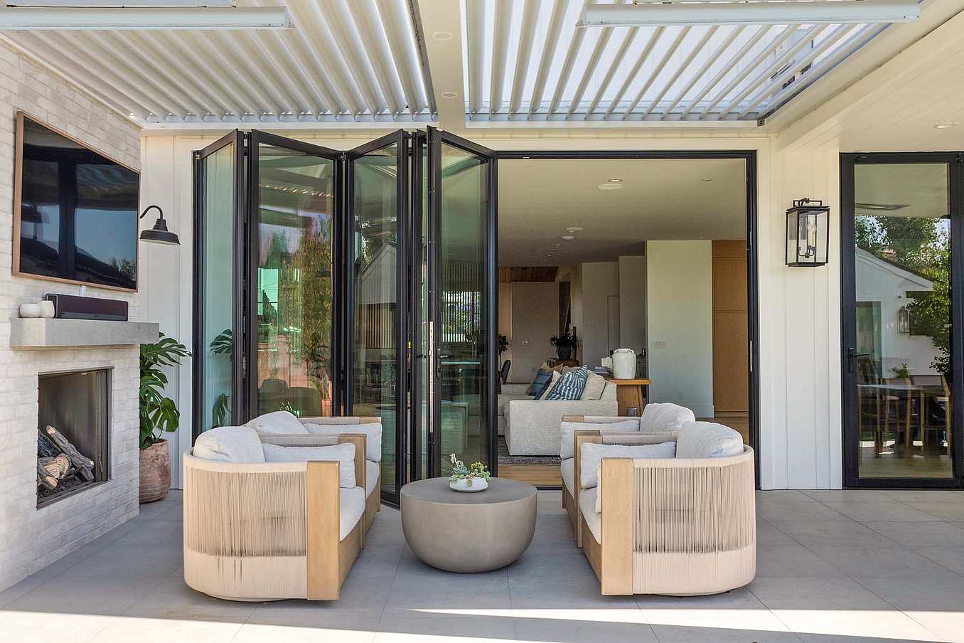 Accordion glass doors partially open to connect your interior to the patio, creating seamless indoor-outdoor flow with natural light