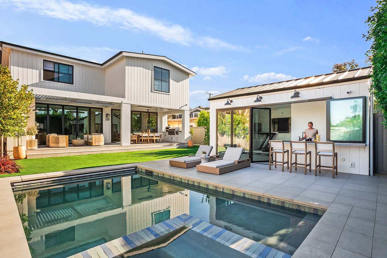Accordion glass doors partially open, seamlessly connecting your interior to the pool area, enhancing natural light and modern living flow