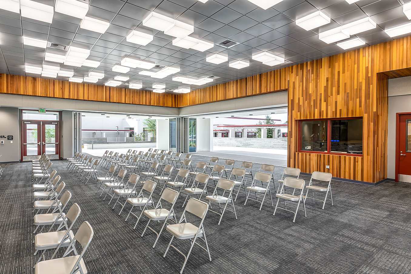 School conference and event room with commercial glass doors opened to outdoor area, showcasing flexible indoor-outdoor use and bright modern interior design