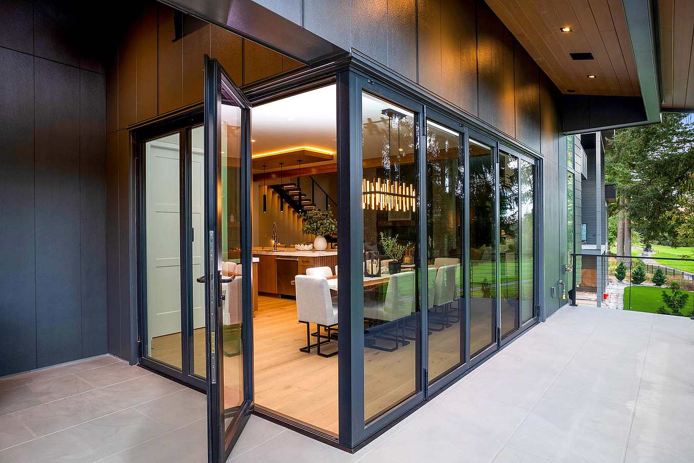 Exterior view of dining room with swing doors open in corner bifold glass system, offering partial access to the outdoor patio