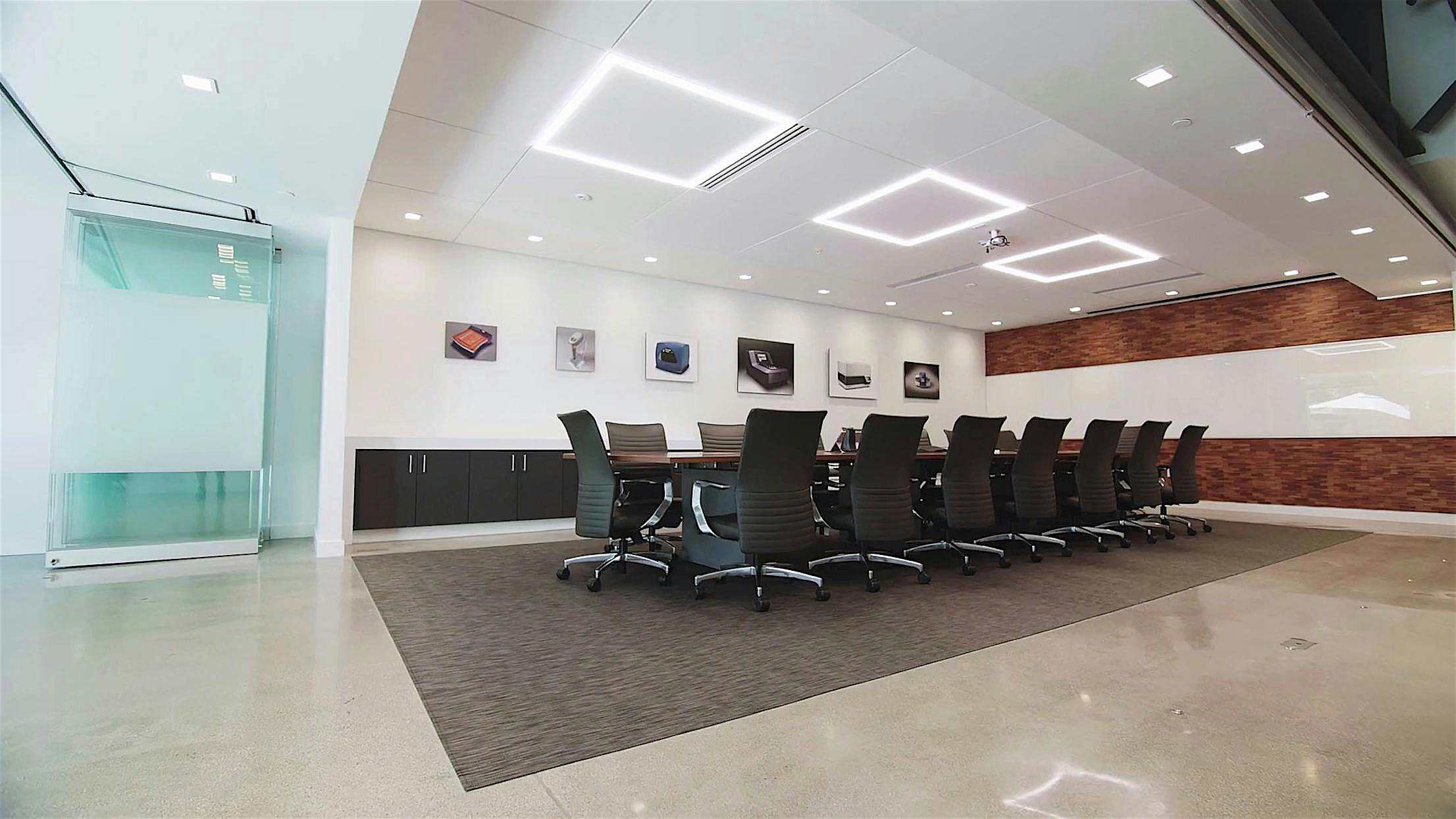 Modern office space with a glass-enclosed conference room with sliding doors and open corner layout.
