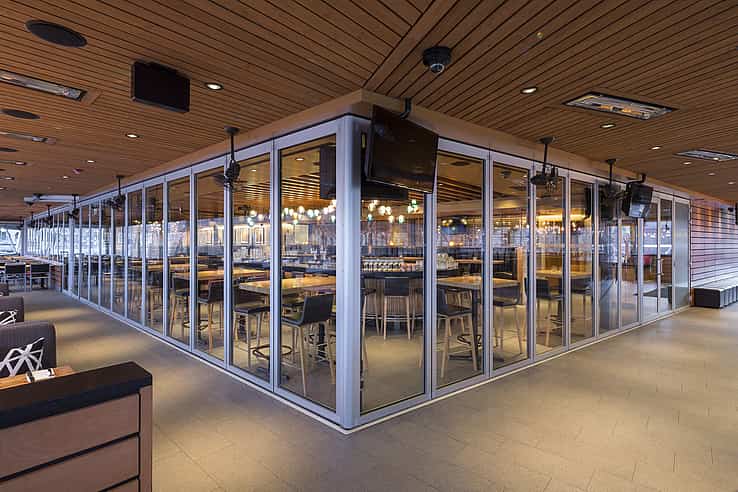 Modern restaurant with aluminum-framed glass wall partitions closed to create a flexible space by separating indoor and outdoor dining areas.