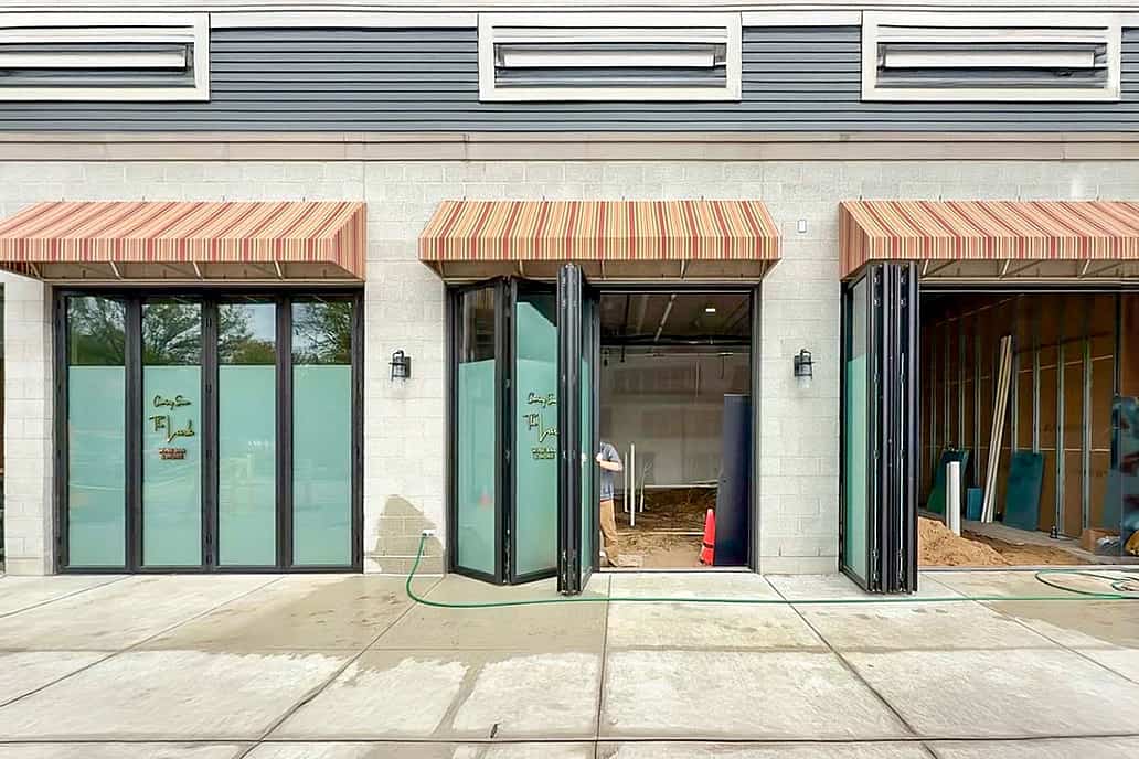 A building exterior features bifold glass doors, enhancing the hospitality design.