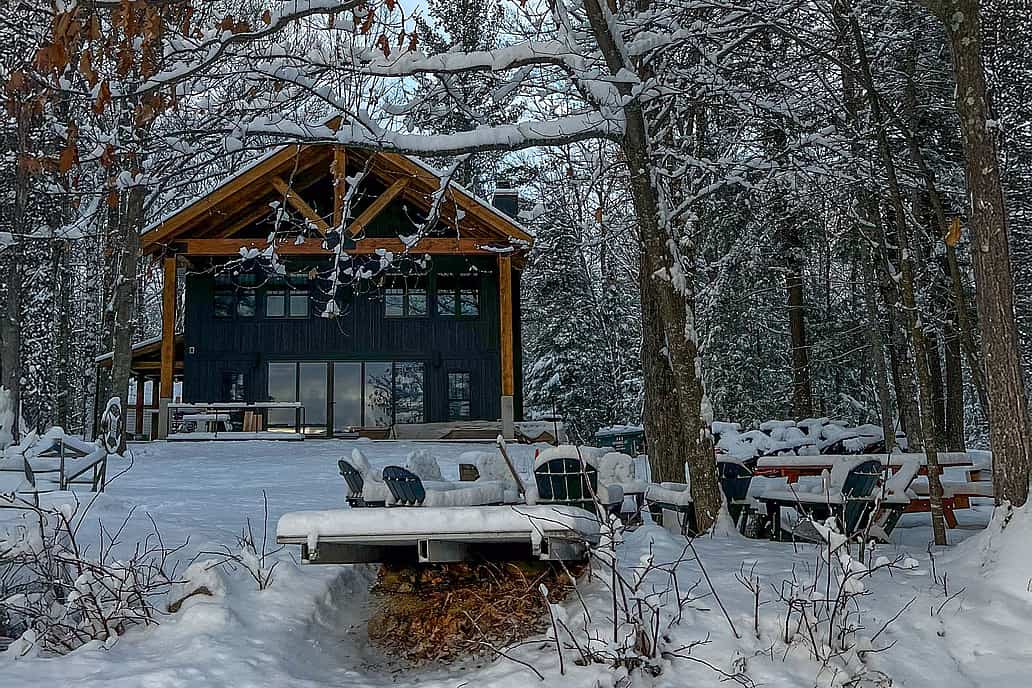 Lake house featuring NanaWall NW Aluminum 640 thermally broken folding glass doors with snow-covered forest and lake views