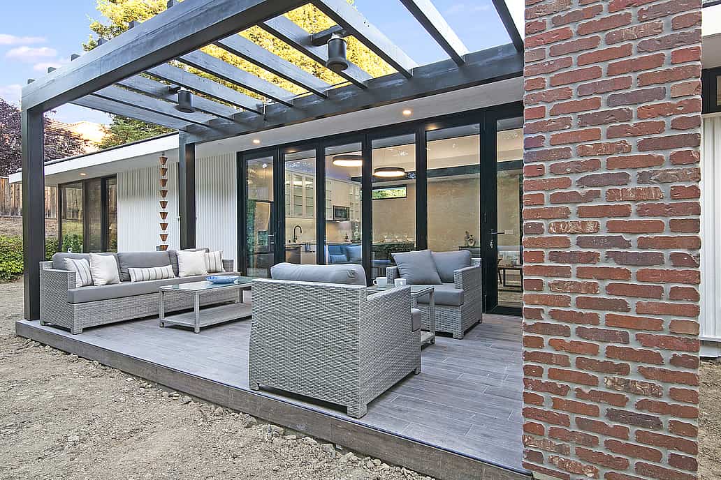 A modern patio with furniture and a brick wall featuring an Aluminum Clad Folding Glass Wall