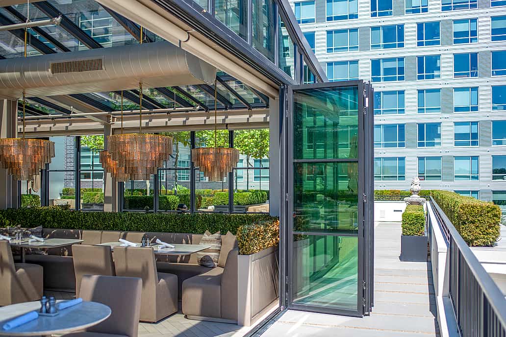 Restoration Hardware rooftop restaurant in Raleigh NC featuring NanaWall SL70 bifold glass doors fully opened to expand the modern outdoor dining area with city views