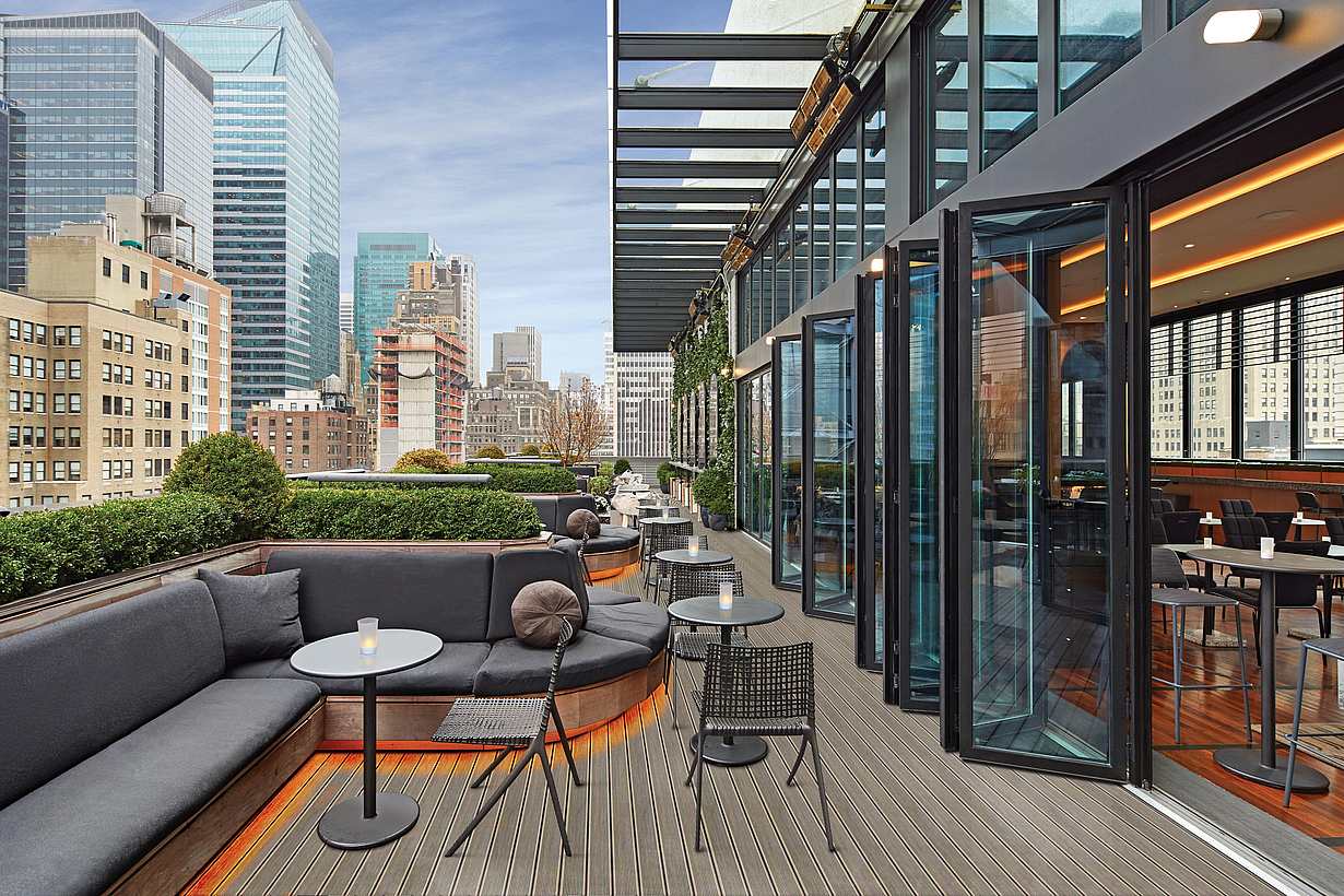 rooftop bar and restaurant in new york city with folding glass walls open to the balcony