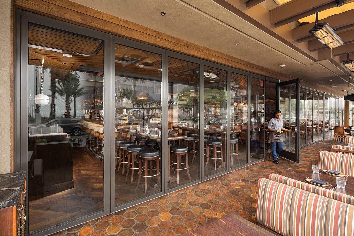 commercial design in restaurant with stacking glass wall and server using swing door