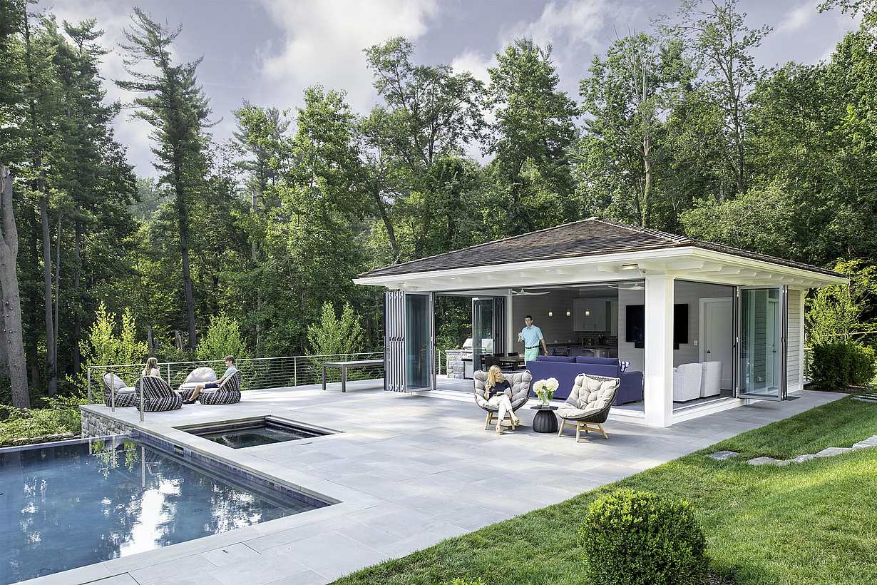 Modern pool house ADU with bifold glass doors opening to lounge and kitchen by the pool