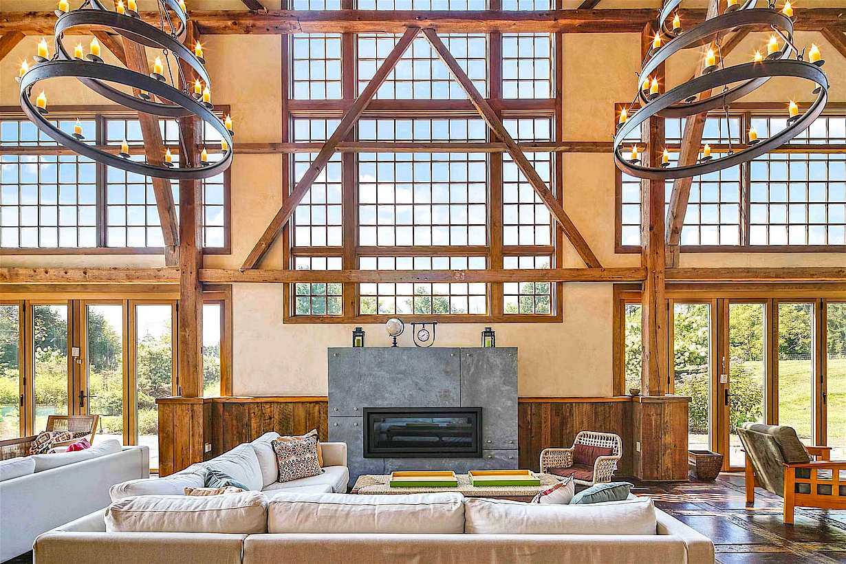 Spacious barn conversion living room with timber framing, tall windows, and patio doors bringing natural light inside