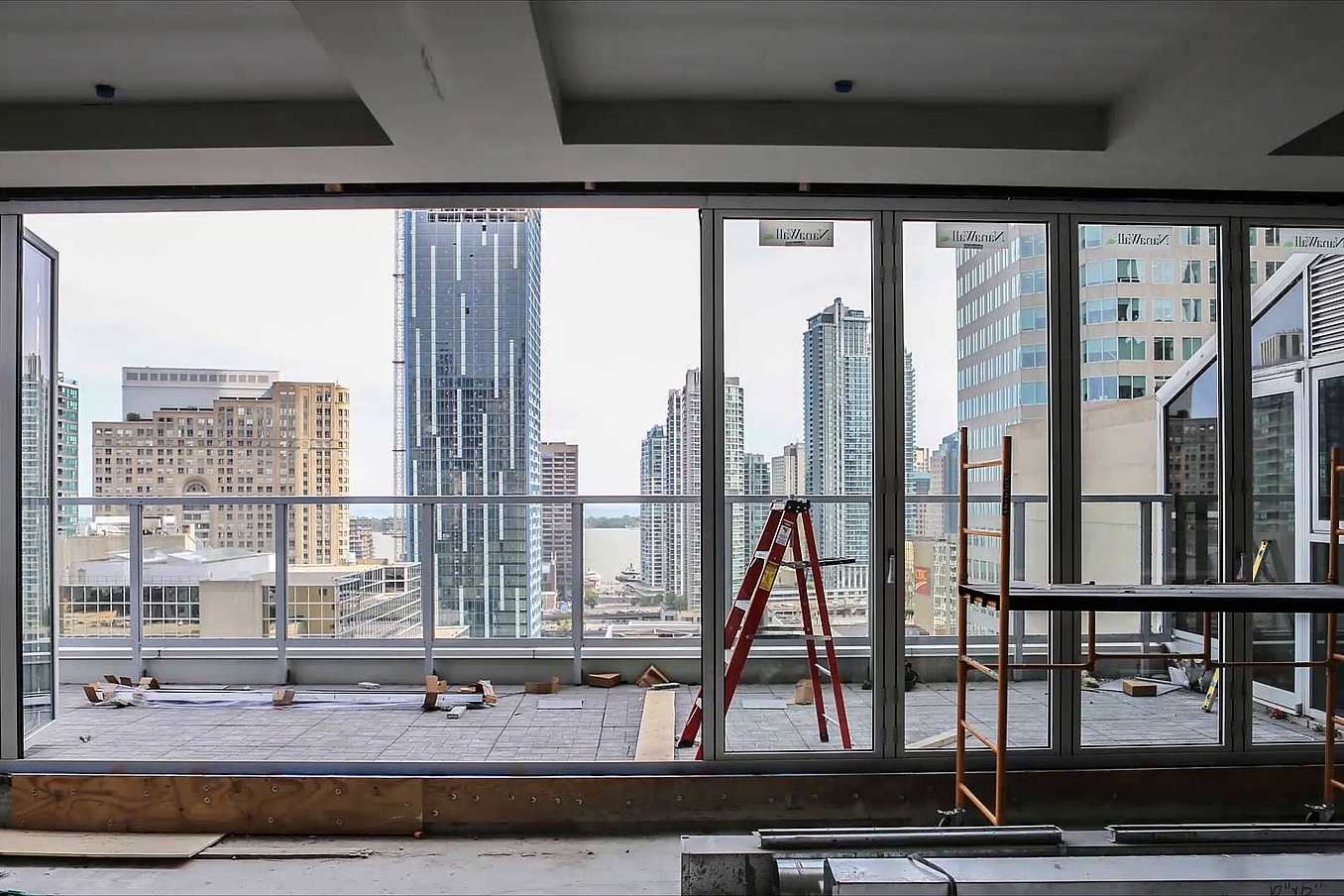 Interior of high-rise under construction with large glass windows and doors installed by NanaWall certified installation network.