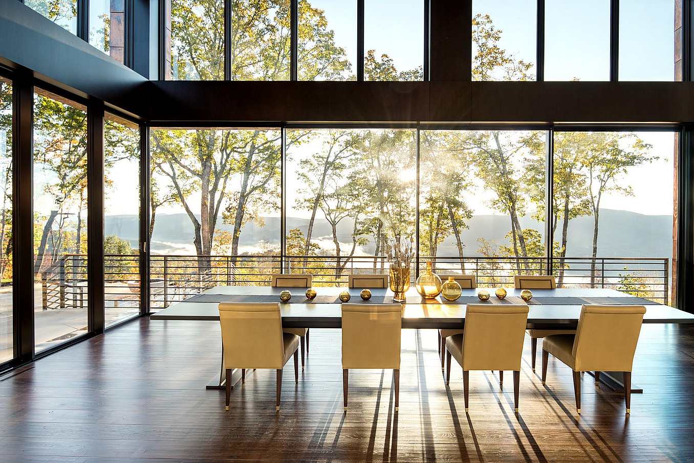 Contemporary dining room with panoramic glass doors opening to scenic mountain view.