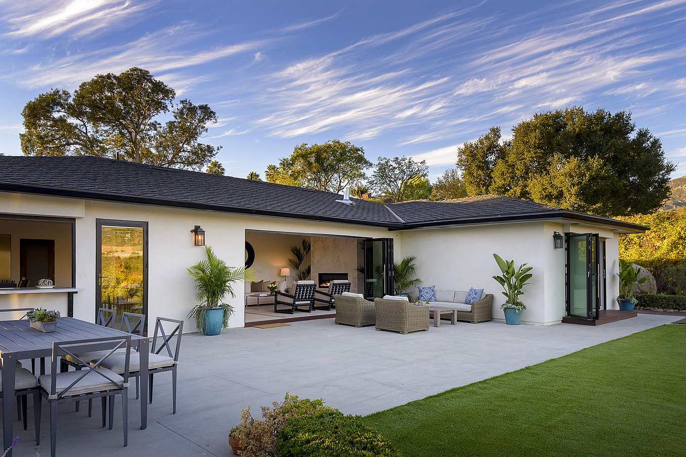 Santa Barbara modern home with folding glass patio doors opening to ocean views, blending indoor-outdoor living with sleek coastal design.