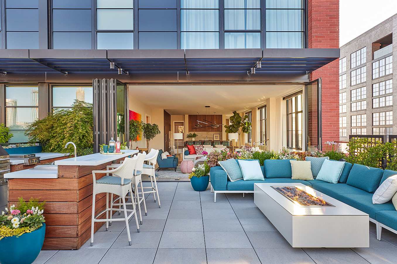 A rooftop patio with outdoor furniture and folding glass walls