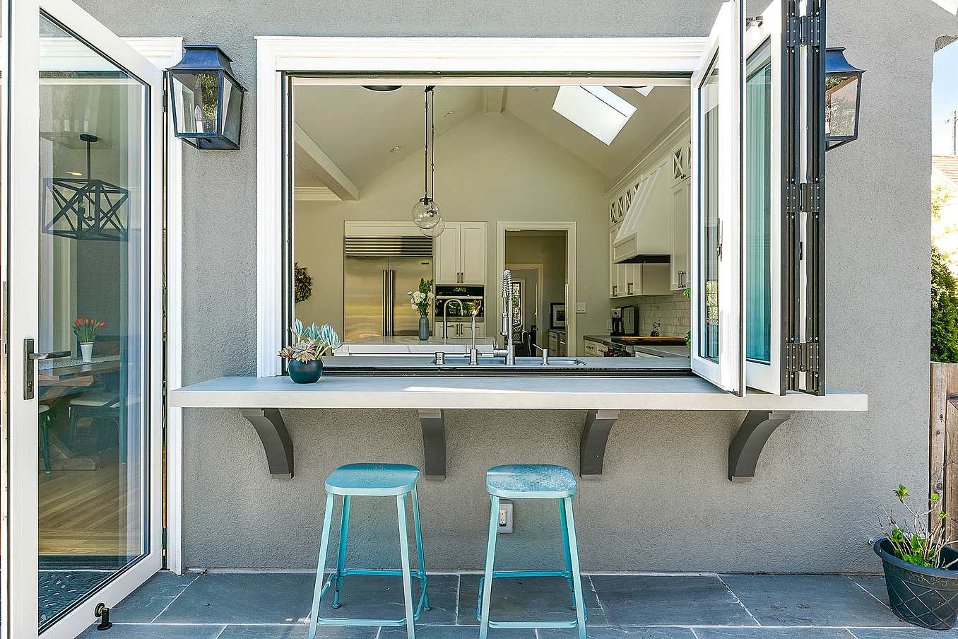 Modern kitchen with outdoor bar with a large open window ledge featuring aluminum clad folding windows, seamlessly connecting to the modern kitchen.