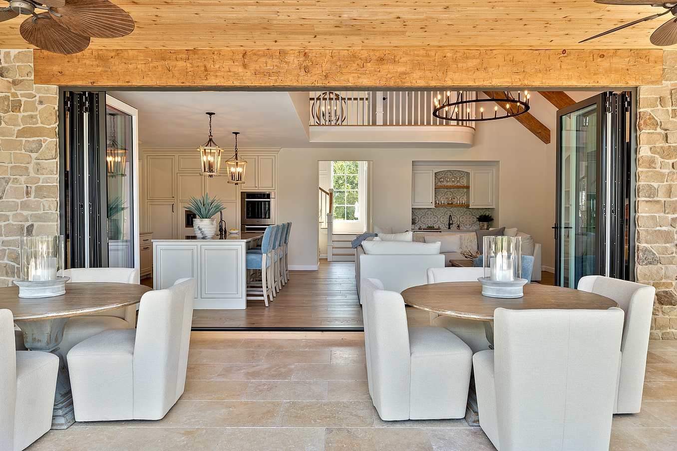 Bright open-plan kitchen and living room with bifold doors and patio dining on stone tiles.