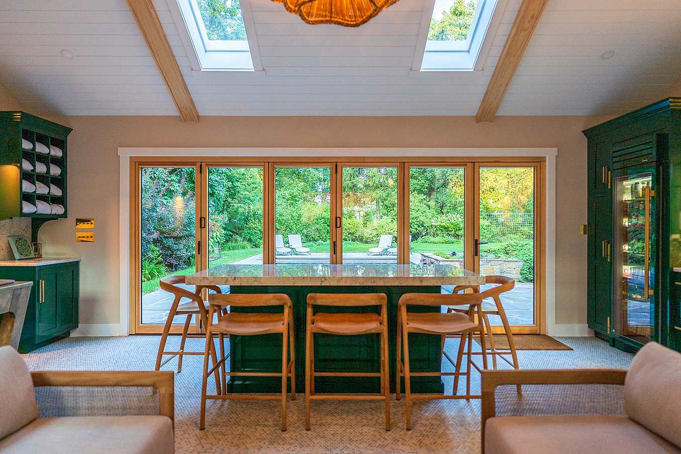 Interior view of a modern kitchen with wood-framed folding glass doors leading to a backyard with a pool.