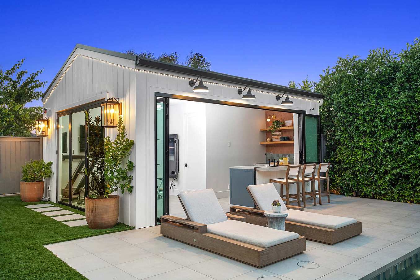 Accordion glass doors open the stylish ADU to the pool area, flooding the space with natural light and creating seamless indoor-outdoor flow