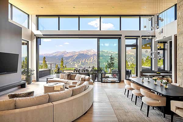 Large panel sliding glass walls offer an uninterrupted view of coastal mountains, lush greenery, and the ocean.
