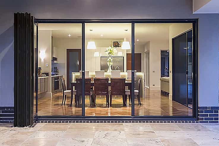 A modern dining room with large sliding glass doors, featuring fully retractable screening feature.