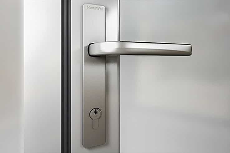 Close-up of a modern stainless steel lever handle and keyhole on a frosted glass door.