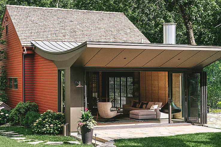 Red barn-style home with large NanaWall SL60 folding glass doors open to patio
