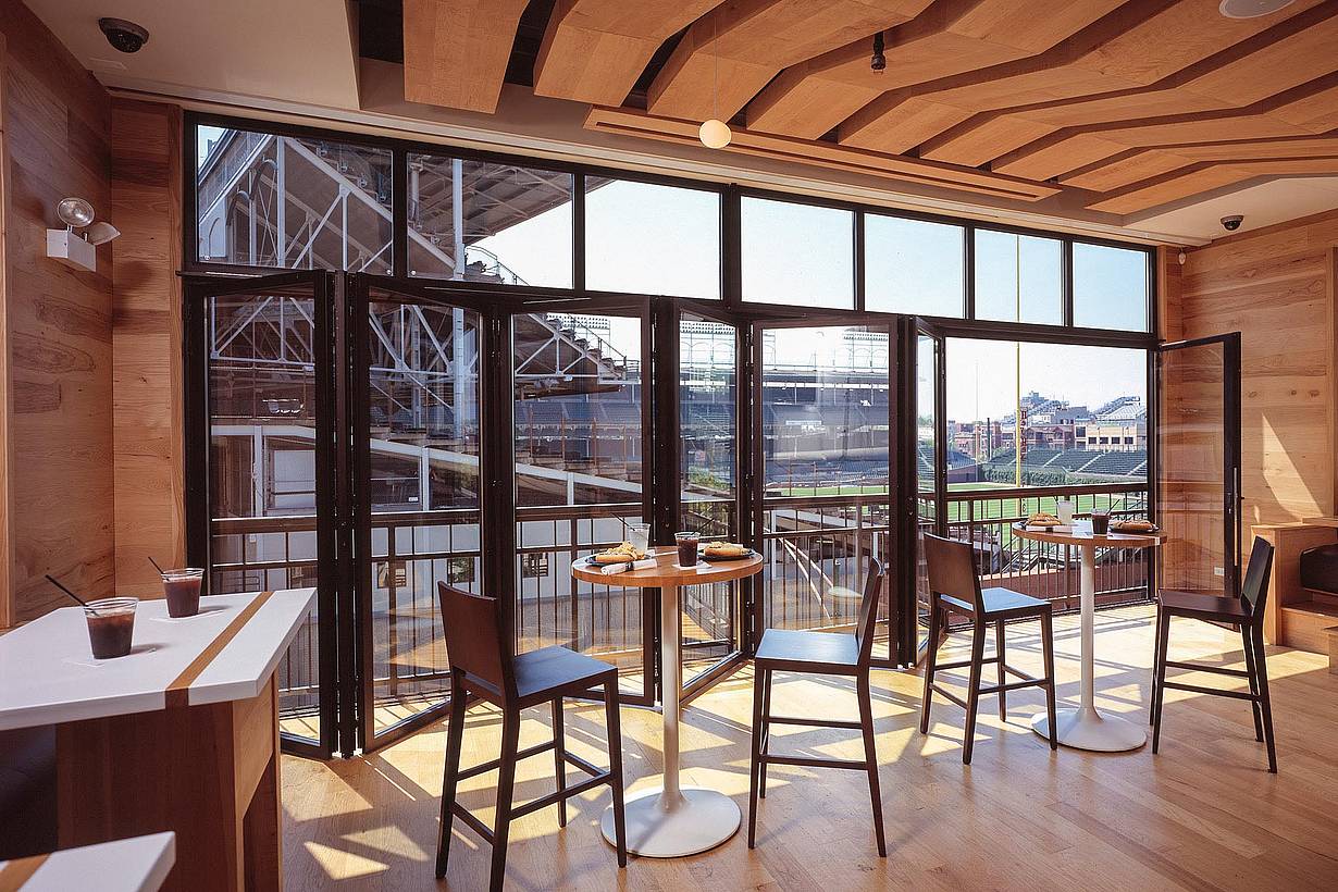 commercial folding glass wall system partially open with view of baseball view for live games