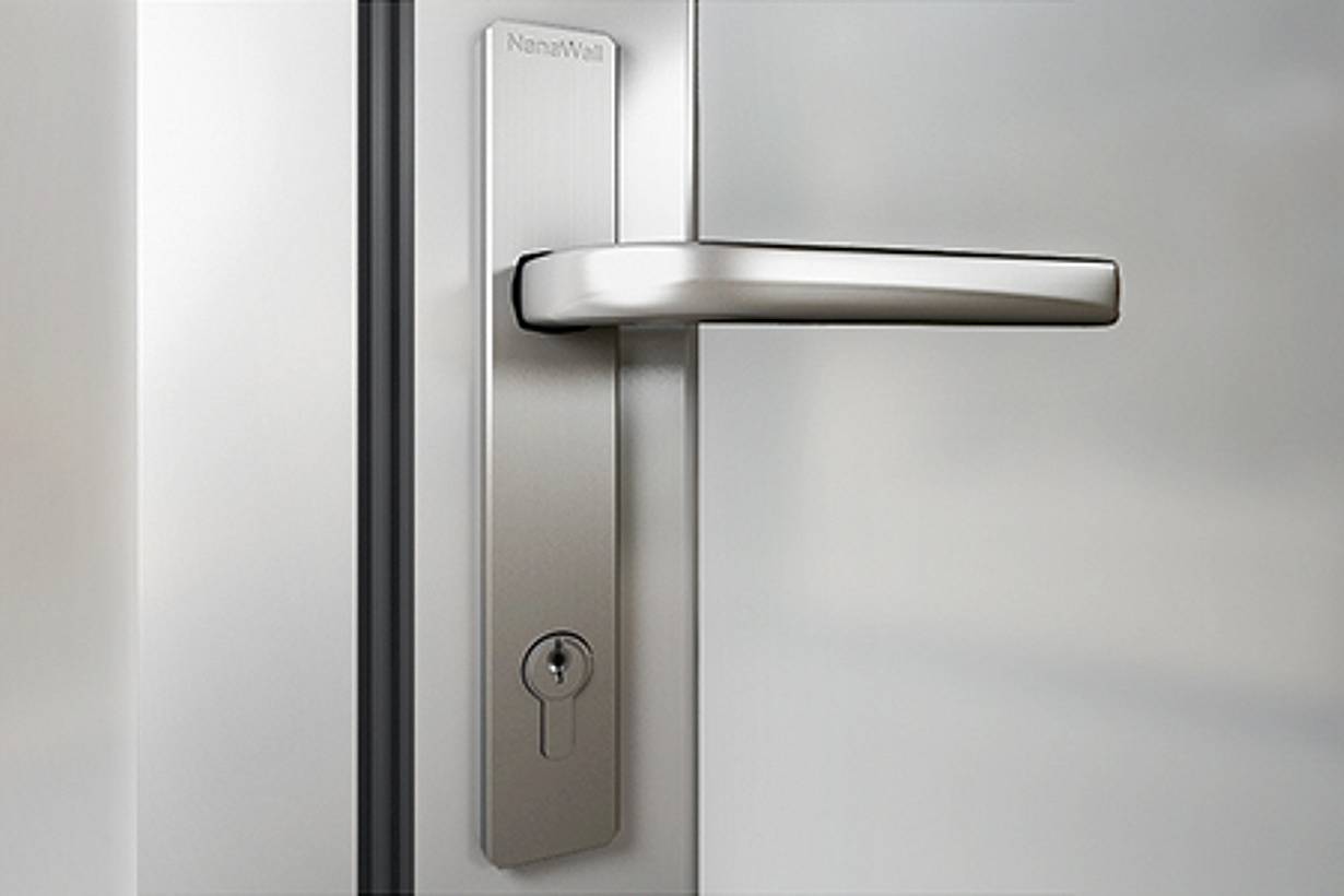 Close-up of a modern stainless steel lever handle and keyhole on a frosted glass door.