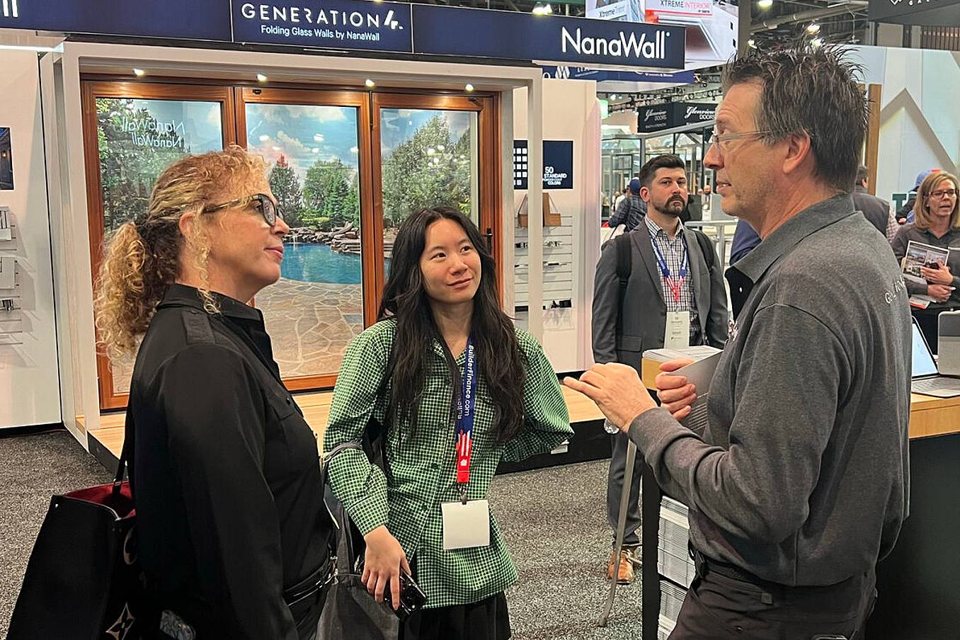 NanaWall Sales Team members stand and talks at a NAHB show booth featuring Generation 4 Folding Glass Doors.