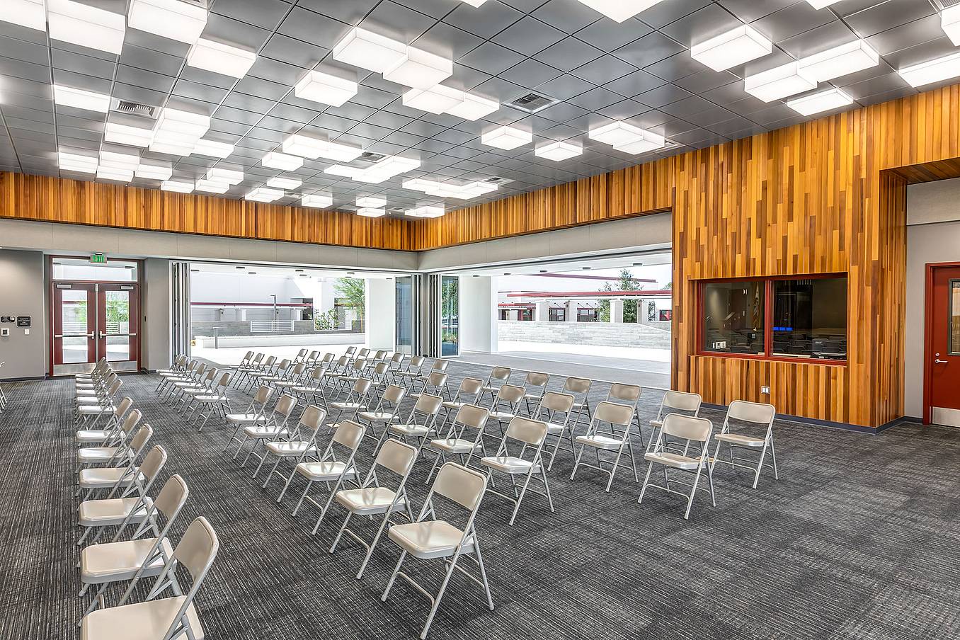 School conference and event room with commercial glass doors opened to outdoor area, showcasing flexible indoor-outdoor use and bright modern interior design