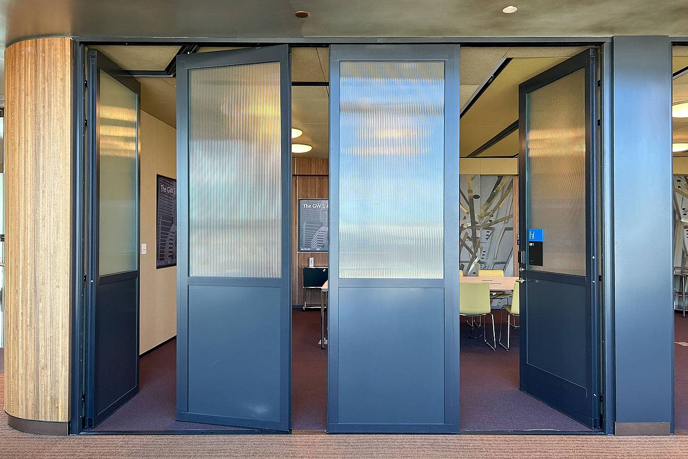 Partially open stacking glass doors by NanaWall creating flexible meeting spaces in a commercial interior