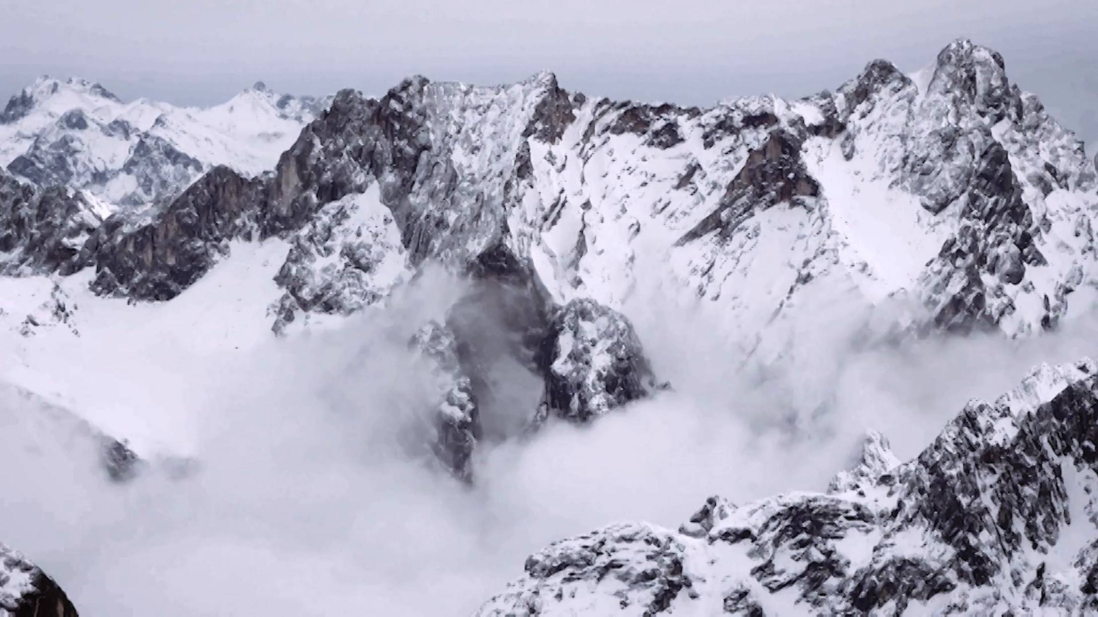 Snow-covered mountain peaks with mist drifting through rocky crevices under a cloudy sky, video vignette featuring high weather performance glass doors.