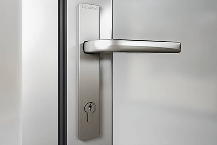 Close-up of a modern stainless steel lever handle and keyhole on a frosted glass door.